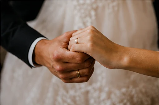 Las manos de los novios entrelazadas mostrando sus argollas