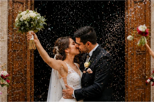 Los novios besándose bajo una lluvia de confeti a la salida de la iglesia